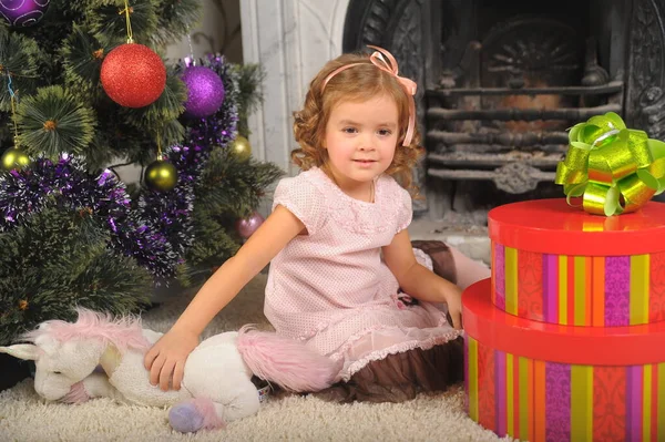 一个快乐的小女孩 穿着一件礼物盒在圣诞树旁的裙子 — 图库照片
