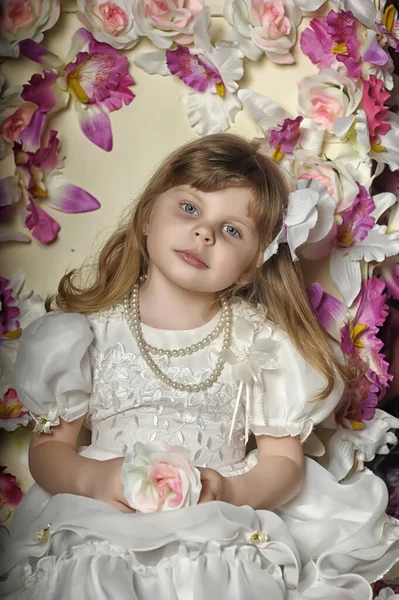 Klein Meisje Een Witte Jurk Een Stoel Met Bloemen — Stockfoto