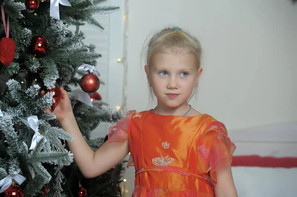 Little Cute Girl Blondynka Pomarańczowej Sukience Przez Choinkę — Zdjęcie stockowe