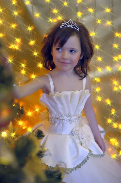 小可爱的小公主 穿着时髦的白色圣诞礼服 坐在金黄色的圣诞树旁 — 图库照片