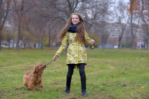 一个穿着夹克的女孩在公园里遛狗玩耍 — 图库照片