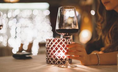 Kadın el ile mum aydınlatma akşam bir restoranda şarap tutar. Sosyal bir akşam yemeği ya da bir parti.