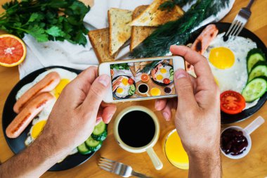 Erkek el telefon üstten görünüm üzerinde Amerikan kahvaltı bir resmini çek. Gıda blogger