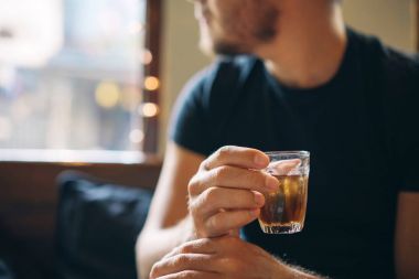 Serinletici bir kafe arka planda bir adamın elinde kahverengi çay soğuk bir bardak.