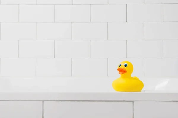 Juguete pato amarillo en el baño sobre un fondo de ladrillo claro — Foto de Stock