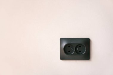 siyah Çift Kişilik elektrik prizine bir hafif pembe duvar. Kavram elektrik ve minimalizm.