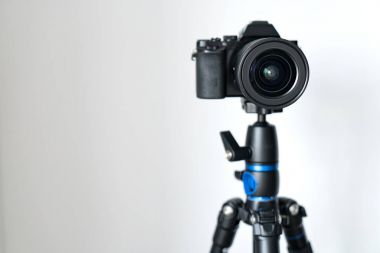 profesyonel siyah aynasızlar kamera bir tripod karşı beyaz bir duvar üzerinde duruyor. Bloglama ve video fotoğraf çekim.
