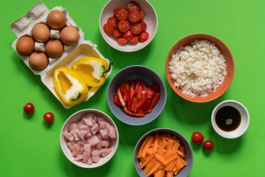Tayland pirinç yemek pişirmek için malzemeler: Beyaz pirinç, domates, biber, soya sosu, yumurta, tavuk eti, havuç. Yeşil bir arka plan üzerinde gıdalar.