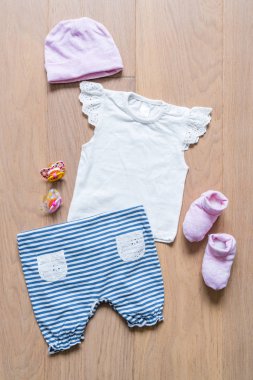 Birtakım elbise ve maddeler için ahşap arka plan üzerinde çocuk T-shirt, pantolon, çorap ve emzikler