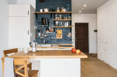 Tavan ve rustik tarzı modern ev mutfak tasarımı. Siyah duvar rafları, tepsiler, kavanoz, bardak ile. Buzdolabı, yemek masa, koridor, tuğla duvar, kapı. Konut çatı stüdyo.