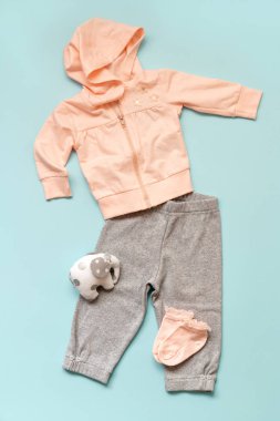 pembe çocuk giyim mavi bir arka plan üzerinde kümesi. Bir başlık ile gri pantolon, çorap ve bir filin oyuncak twist. Çocuk için moda seçimi.