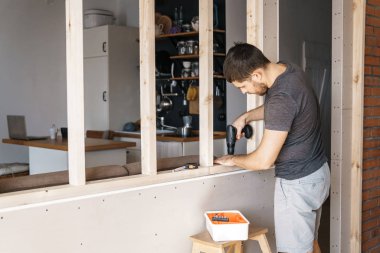 Bir adam elinde tornavidayla evinde bir ahşap çerçeve penceresi için giderir. Kendiniz tamir.