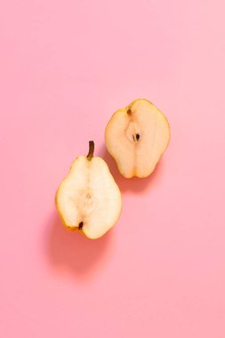 Arka plan iki yarısı kesilmiş sarı armut üzerinde bir pastel pembe.