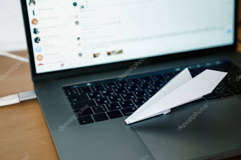 telegram white paper airplane on the gray laptop keyboard and screen.