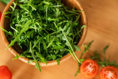 Ahşap ahşap arka plan üzerinde kiraz domates ile taze yeşil, doğal roka kâse