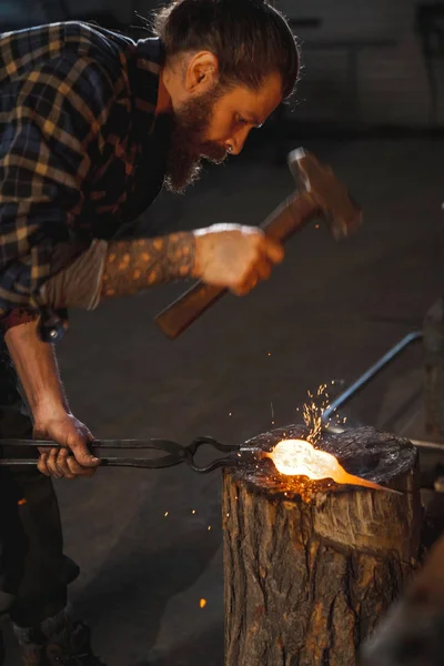 ひげを持つ男の残忍な鍛冶屋は ホット アイテムを作ってハンマーで彼のワーク ショップで動作します 専門職の肖像画 — ストック写真