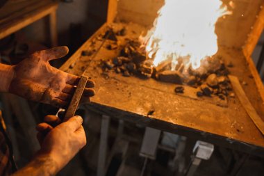 Demirci el metal bir parça demirci dükkanında bir alev arka plan karşı tutun. İnsanlar ve meslekler.
