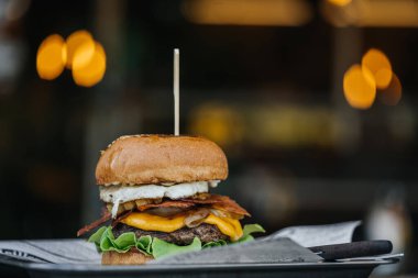 Daha büyük lezzetli hamburgerler et ve yumurta ile bir masada sokak bokeh.