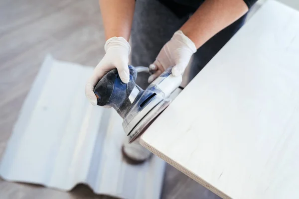 Arbeiter im Prozess der Holzbearbeitung, eine Frau mit einem Werkzeug in der Hand der Maschine zum Schleifen der Oberfläche. — Stockfoto