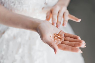 Avucunda altın alyanslar tutan bir gelinin elleri. Düğün konsepti