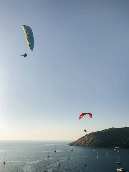 Fallschirmspringer fliegen über das Meer vor dem Hintergrund eines wunderschönen Sonnenuntergangs, Inseln und Yachten. — Stockfoto