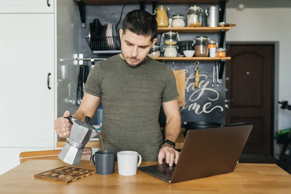 Привлекательный Мужчина Работающий Ноутбуке Наливающий Кофе Интерьер Домашней Кухни Утром — стоковое фото