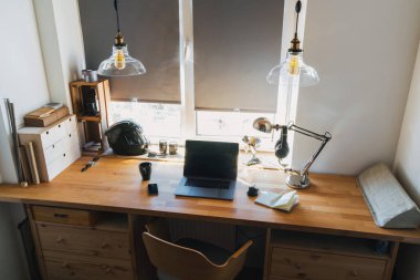 Çatı katında çalışma masası. Tahta masa, dizüstü bilgisayar, pencere, sandalye.