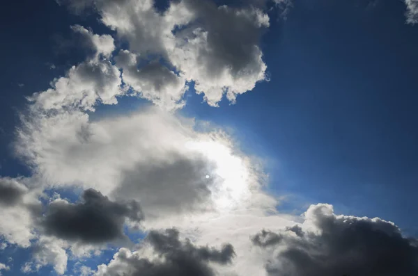 The sun is hidden behind clouds on a blue sky