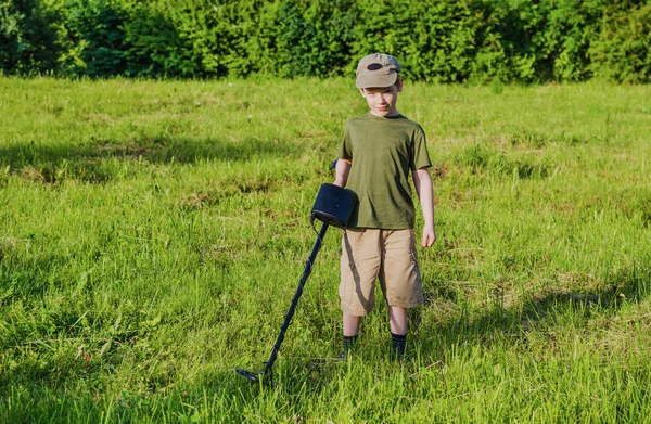 Chlapec s detektorem kovu na zelené louce — Stock fotografie