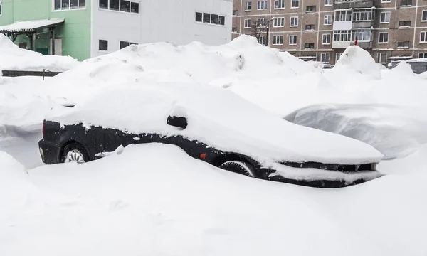 Bil täckt med snö i en urban gård — Stockfoto