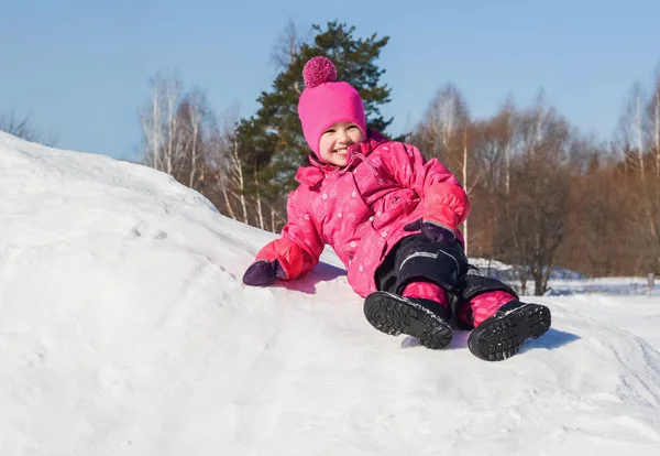 Glad liten flicka på en promenad en klar vinterdag. — Stockfoto