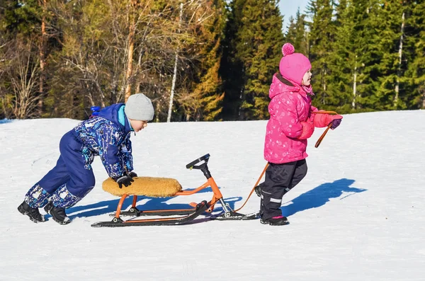 子供たちは雪のスクーターに乗る — ストック写真