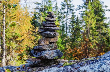 Güneşli bir günde, bir sonbahar ormanının arka planına karşı dağ yamacındaki taşlar piramidi.