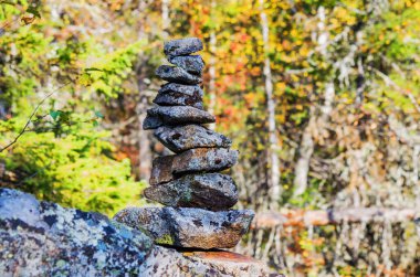 Güneşli bir günde, bir sonbahar ormanının arka planına karşı dağ yamacındaki taşlar piramidi.