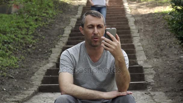 Man In Video Call Outdoor On Stairs Person Walks By — Stock Video