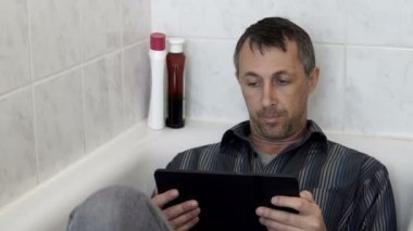 Adam bir Tablet ile Tunceli banyo küvet içinde