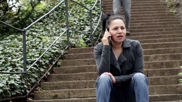 Femme assise sur les escaliers extérieurs sur le téléphone et l'homme descend les escaliers — Video