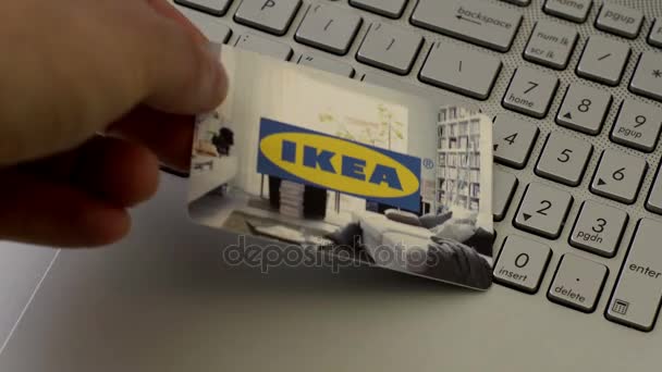 Une personne anonyme met une carte cadeau IKEA sur un ordinateur portable — Video