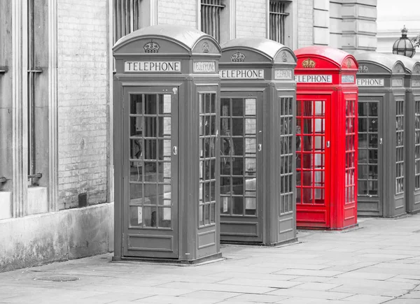 Five Red London Telephone boxes all in a row in black and white with one red phone booth