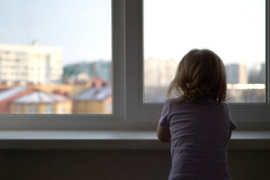 Pencerenin önünde duran küçük bir kız