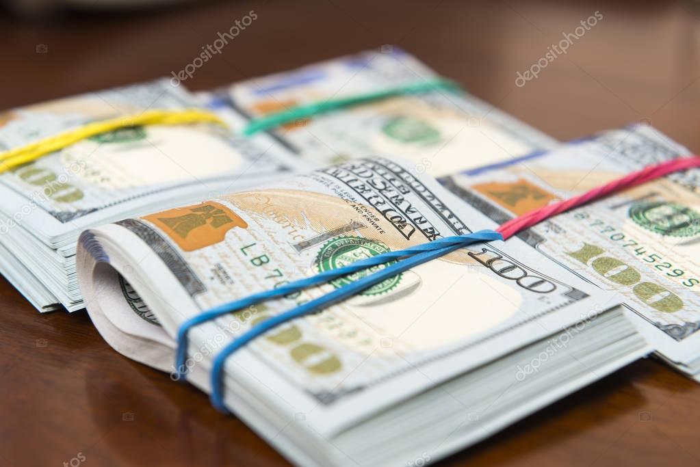 Stashes of hundred dollar bills on wooden table