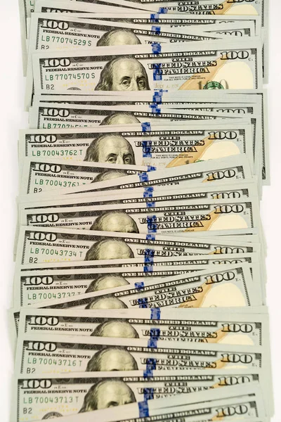 Wiele kilkuset dolarów banknotów rozprzestrzenił się na białej powierzchni — Zdjęcie stockowe