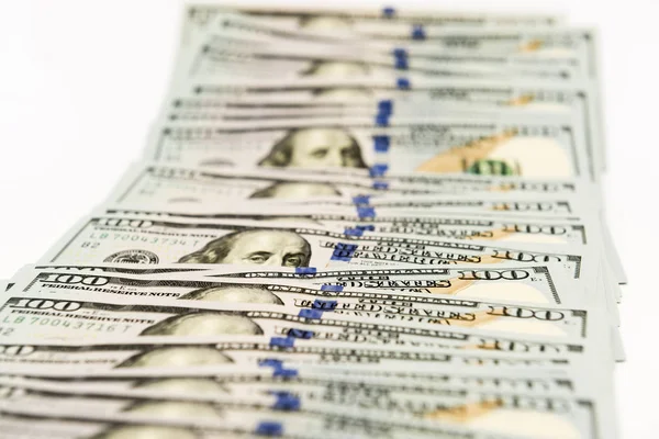 Банкноты стоимостью в сто долларов разбросаны по белой поверхности — стоковое фото