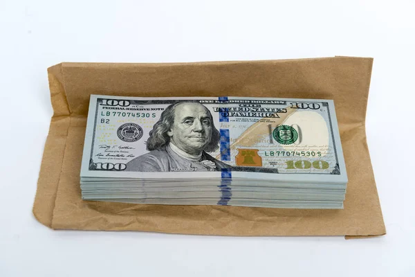 Пачка долларовых банкнот и коричневый конверт — стоковое фото