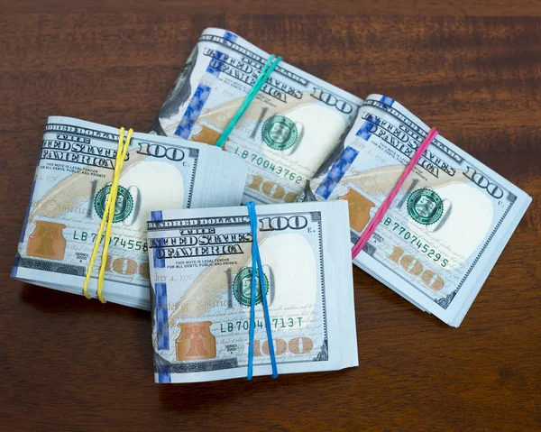 Depósitos de billetes de cien dólares en la mesa de madera Imágenes de stock libres de derechos