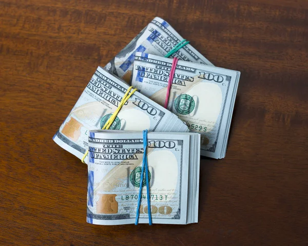 Escoamentos de notas de cem dólares na mesa de madeira Fotografias De Stock Royalty-Free
