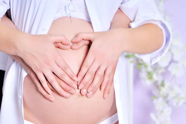 妊娠中の女性や心臓の形で手をつないでの夫 — ストック写真