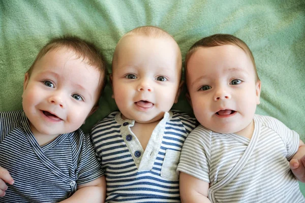 Portrait of newborn triplets are lying in the bed — Stock Photo, Image