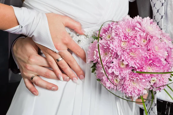 新郎和新娘的手躺在 p 婚礼花束背景 — 图库照片