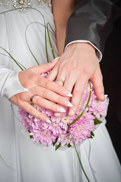 Le mani di sposo e sposa si trovano su sfondo bouquet di nozze di p — Foto Stock